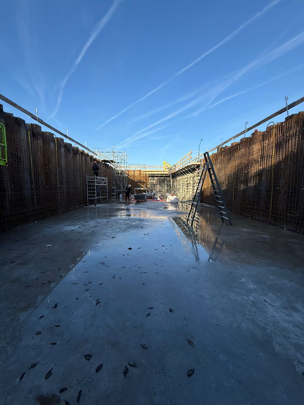 De bouwkuip met stalen damwanden onder een blauwe winterlucht