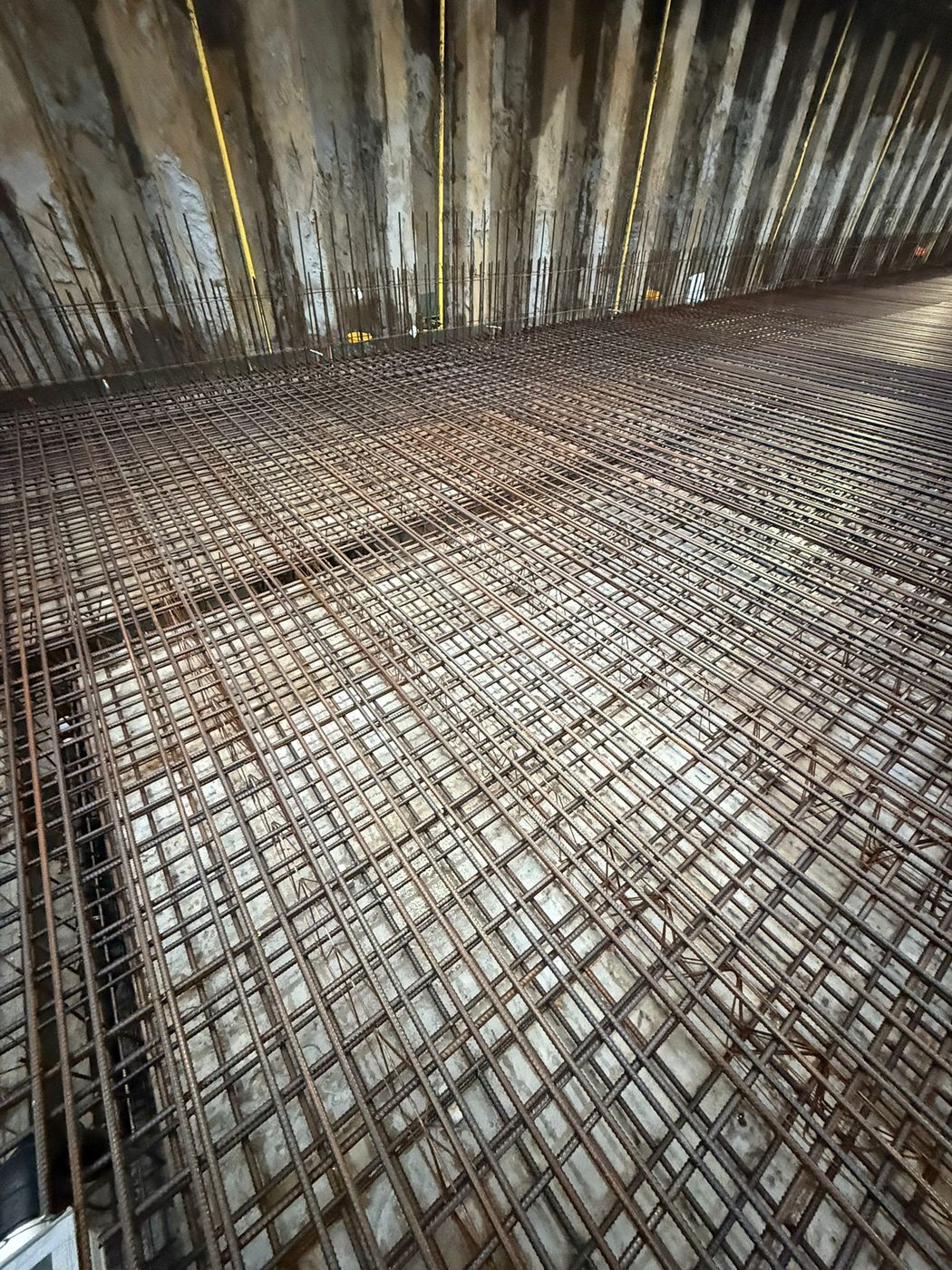 Hoek van de keldervloer, met de wapening doorgekoppeld naar de wand