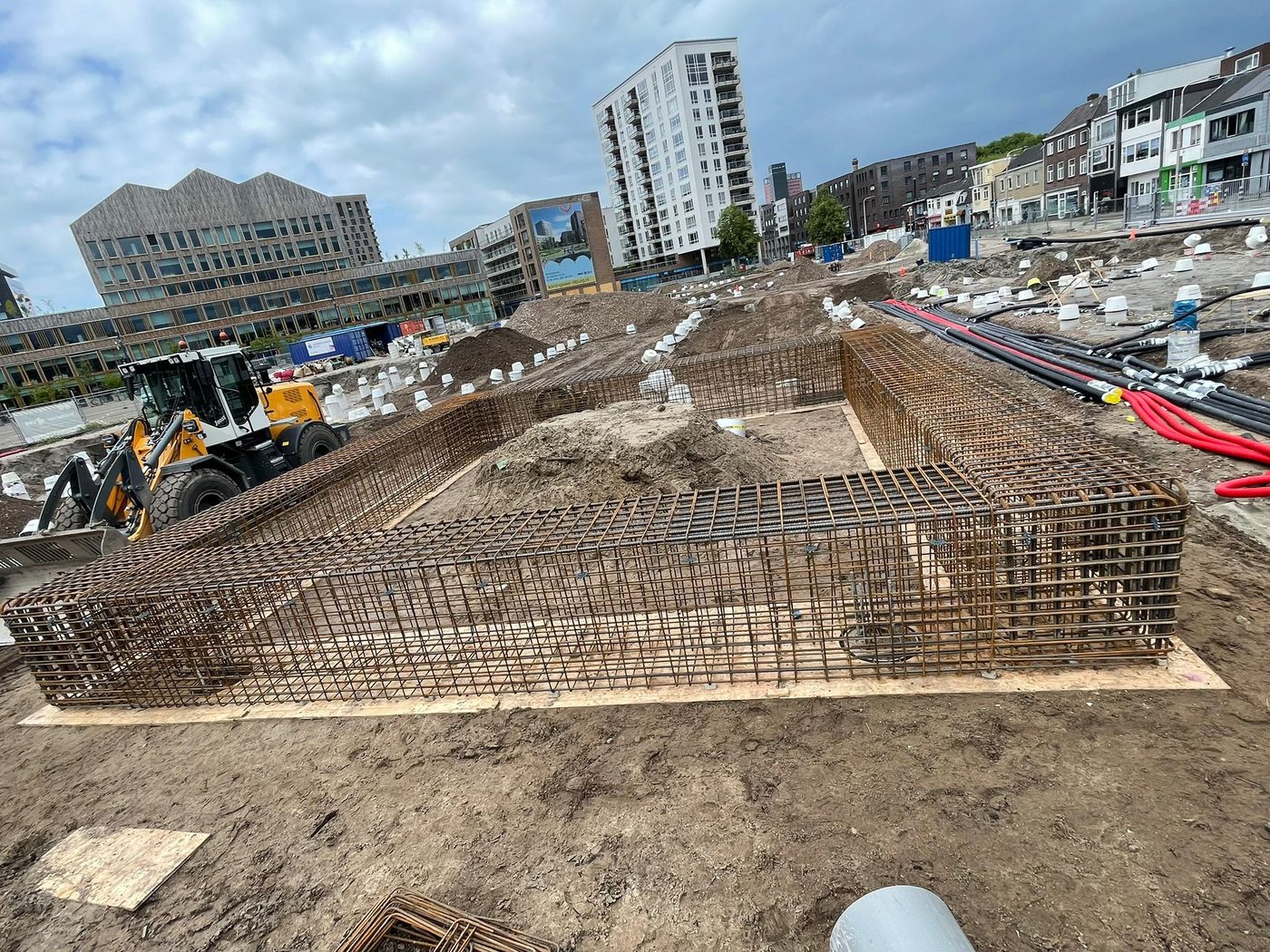 Gewapende funderingsbalken in de bouwkuip aan de Koningswei, met de Tilburgse binnenstad op de achtergrond
