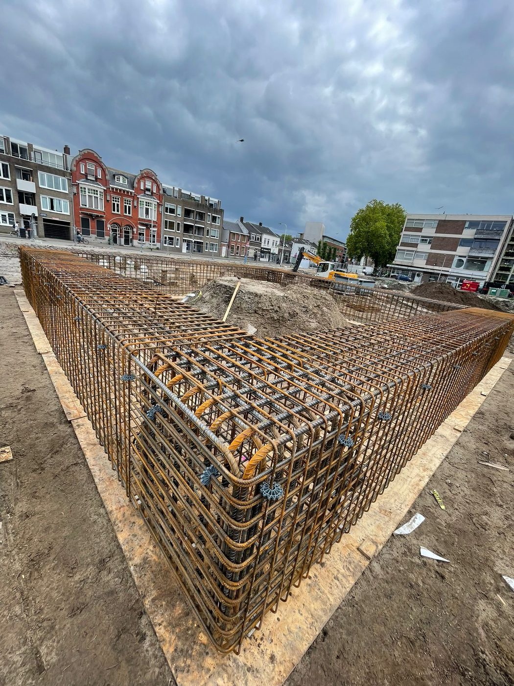 Hoekige wapeningskorf voor een funderingsbalk, met de historische gevels aan het Koningsplein erachter