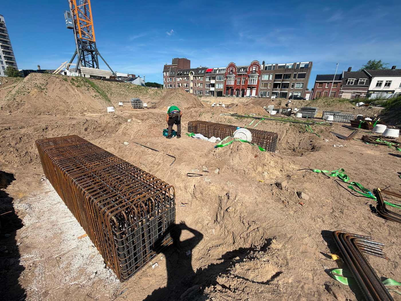 Langwerpige wapeningskorf op de bouwplaats, met de torenkraan op de achtergrond