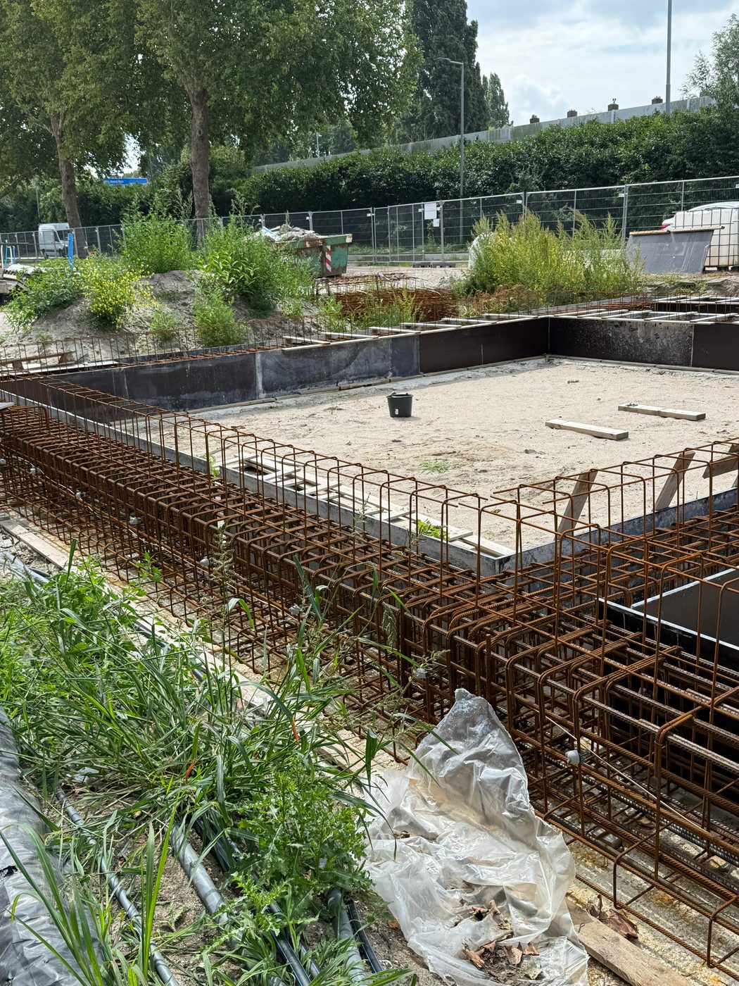Gewapende fundering van een woonblok, gezien vanaf de groenstrook langs de weg